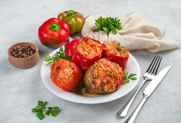 Un piatto con peperoni ripieni in umido con erbe fresche su sfondo grigio