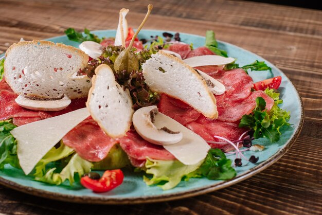 Un piatto con pesce rosso, formaggio e funghi su fondo di legno