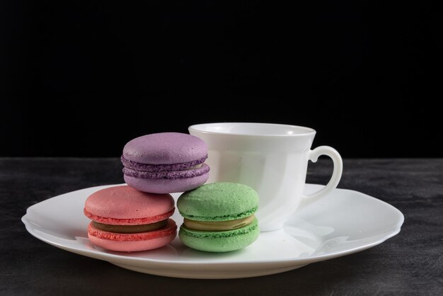 Un piatto con tre amaretti e una tazza di caffè sopra