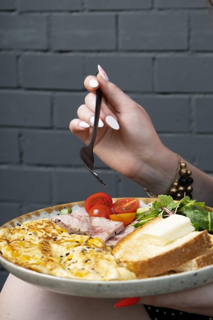 Un piatto con un'omelette con tacchino e verdure mani femminili con una forchetta