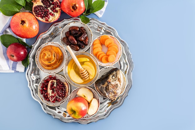 Un piatto d'argento con prelibatezze tradizionali per il capodanno ebraico Il concetto della festa di Rosh Hashanah Vista dall'alto Sfondo blu