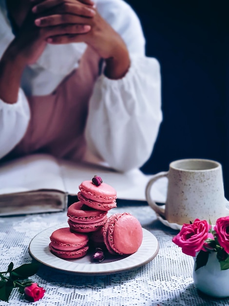 Un piatto di amaretti si trova su un tavolo con una tazza di caffè e un libro che dice "l'amore è sullo sfondo"