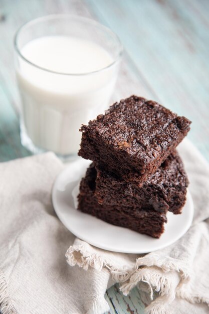 un piatto di brownies con un bicchiere di latte accanto a loro