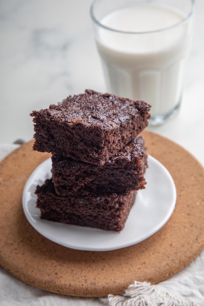 un piatto di brownies con un bicchiere di latte sullo sfondo