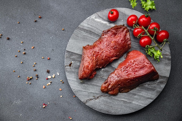 Un piatto di carne con sopra pomodori e prezzemolo