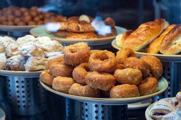 Un piatto di ciambelle fritte croccanti, una vetrina in una pasticceria con pasticcini