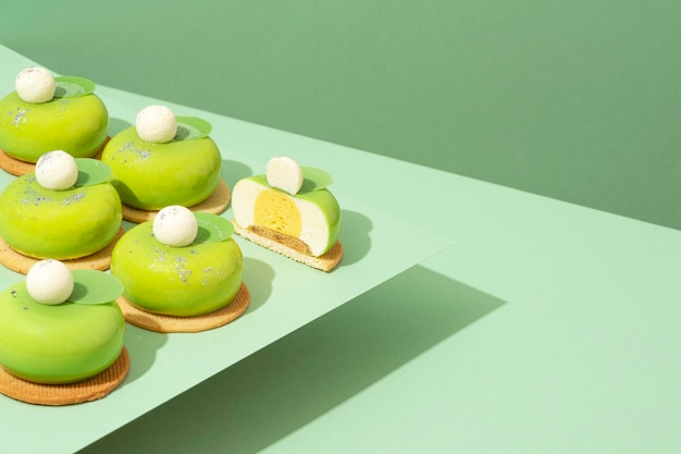 Un piatto di ciambelle verdi assortite si trova in cima a un tavolo di legno