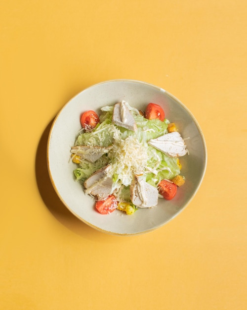 Un piatto di cibo con sopra un'insalata e uno sfondo giallo.