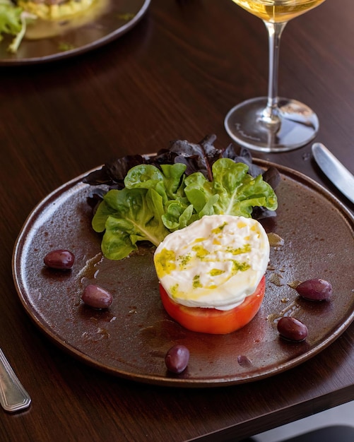 Un piatto di cibo con sopra un pomodoro e un bicchiere di vino sul tavolo.