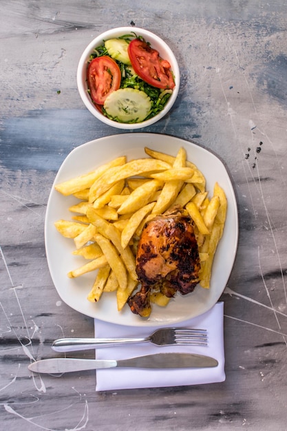 Un piatto di cibo con sopra una ciotola di insalata e pollo