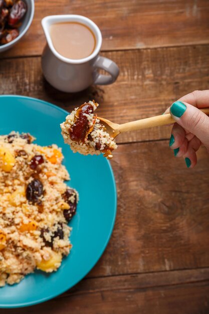 Un piatto di cuscus con frutta secca e noci su un tavolo di legno accanto agli ingredienti