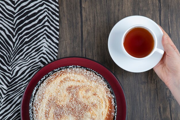 Un piatto di deliziosa torta con una tazza di tè nero posto su un tavolo di legno.