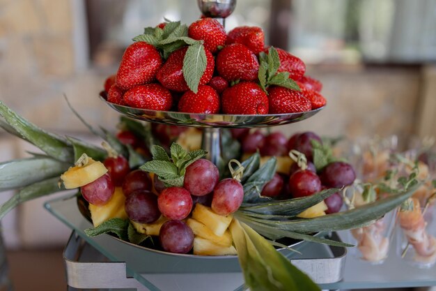 Un piatto di frutta fresca con fragole, uva e ananas splendidamente disposti