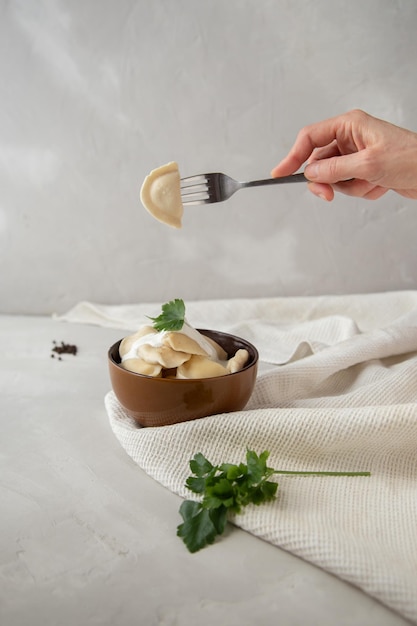 Un piatto di gnocchi con ricotta con panna acida e prezzemolo su uno sfondo grigio chiaro