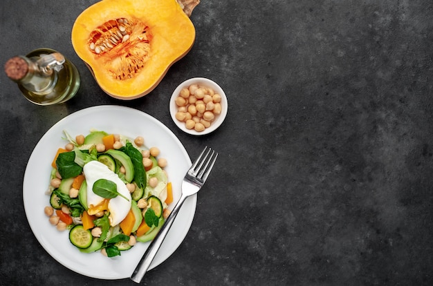 un piatto di insalata di avocado, ceci, zucca, cetriolo, uovo in camicia in un piatto