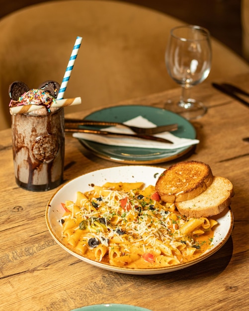 Un piatto di pasta con pane e un bicchiere di gelato a parte