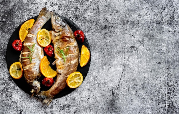 Un piatto di pesce con verdure su uno sfondo grigio