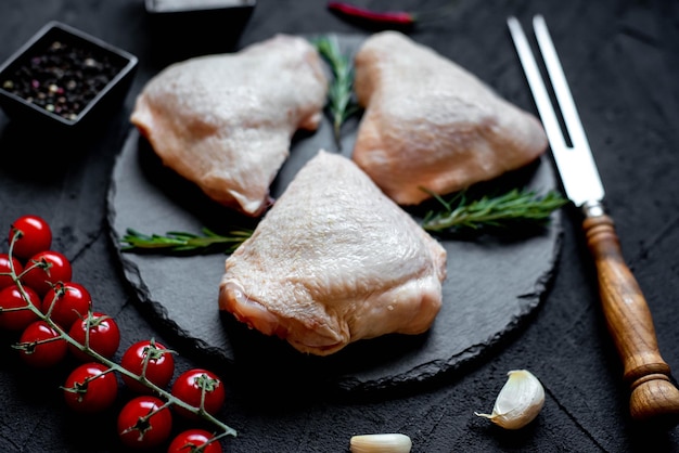 Un piatto di pietra nera con sopra petto di pollo, aglio e pomodori.