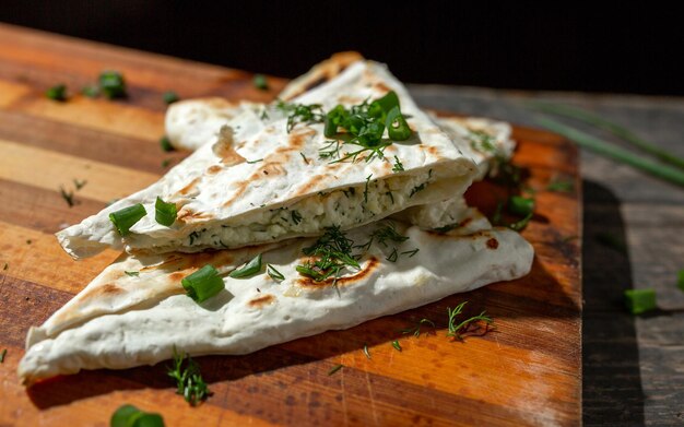 Un piatto di ricotta con prezzemolo e cipolle in pane pita fritto su una griglia giace su una tavola