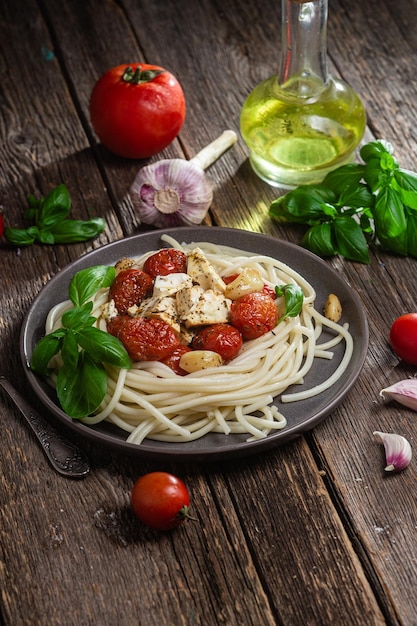 Un piatto di spaghetti con pollo e formaggio su un tavolo di legno.