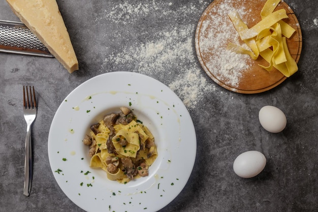 Un piatto di tagliatelle con funghi su un marmo grigio scuro