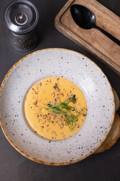 Un piatto di zuppa di crema di formaggio con noci e verdure su uno sfondo scuro vista superiore