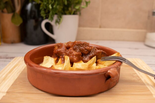 Un piatto rustico di argilla con gulasch e patate posto su una tavola di legno Concetto di cibi tradizionali