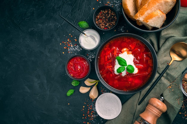 Un piatto tradizionale russo, borscht con panna acida, aglio e spezie su uno sfondo nero. Concetto di cucina.