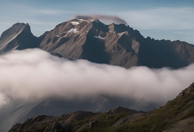 Un picco di montagna tra le nuvole con una nuvola che copre la parte superiore.