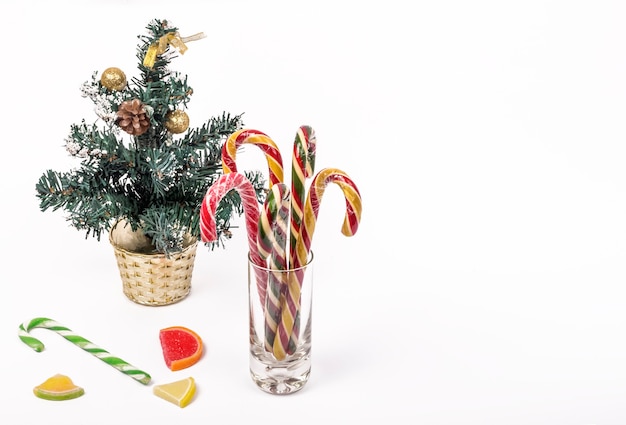 Un piccolo albero di Natale e un bicchiere di dolci natalizi con una copia dello spazio.