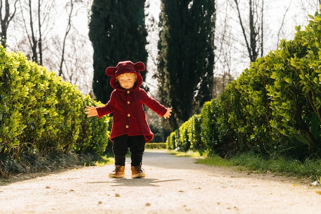 Un piccolo bambino biondo con un bel vestito cammina per il parco al sole