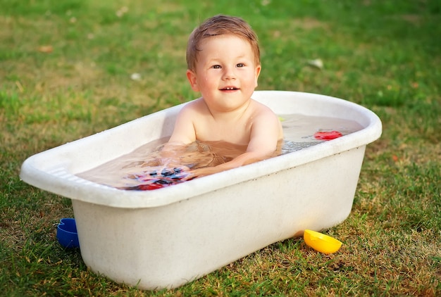 Un piccolo bambino felice ha fatto il bagno nella vasca da bagno e gioca nella vasca da bagno con i giocattoli.