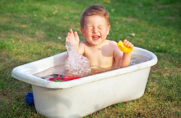 Un piccolo bambino felice ha fatto il bagno nella vasca da bagno e gioca nella vasca da bagno con i giocattoli