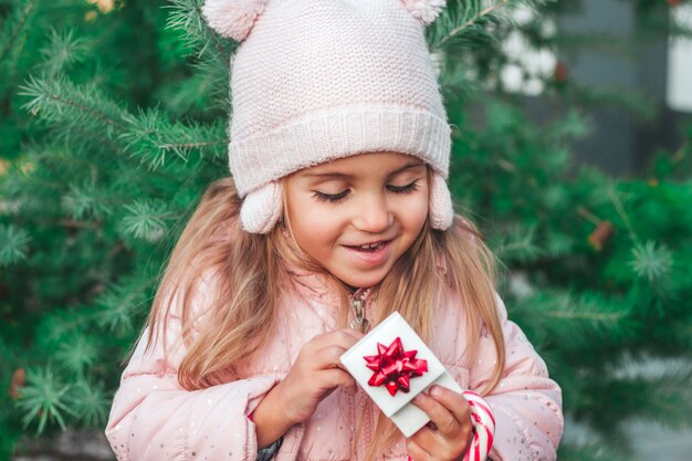 Un piccolo bambino gioisce sorpreso apre un regalo nel parco Natale