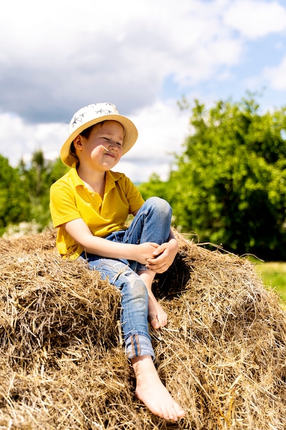 Un piccolo bellissimo bambino è seduto sulla paglia