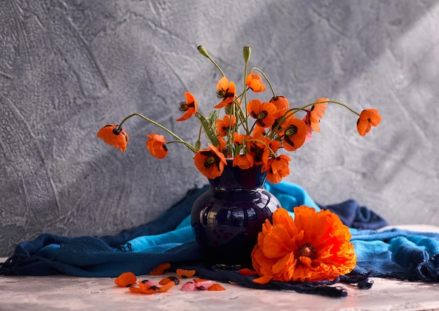 Un piccolo bouquet di papaveri rossi in un vaso di ceramica blu