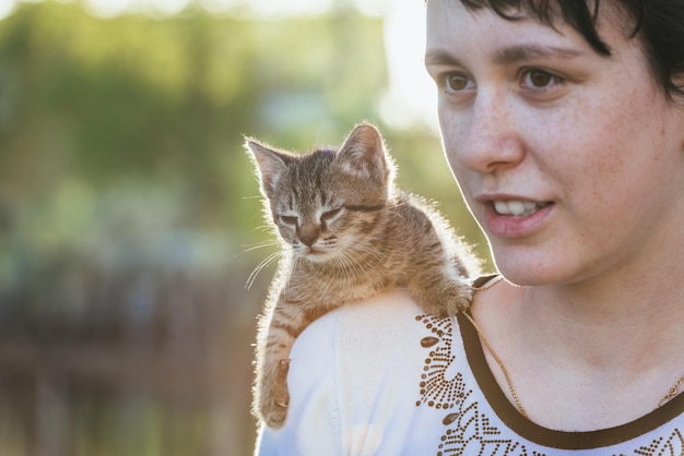 Un piccolo gattino seduto sulla spalla di una ragazza durante una passeggiata