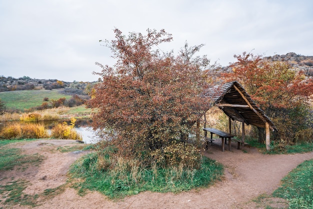 Un piccolo gazebo carino in legno tra splendidi alberi autunnali nella natura delle colline dei Carpazi