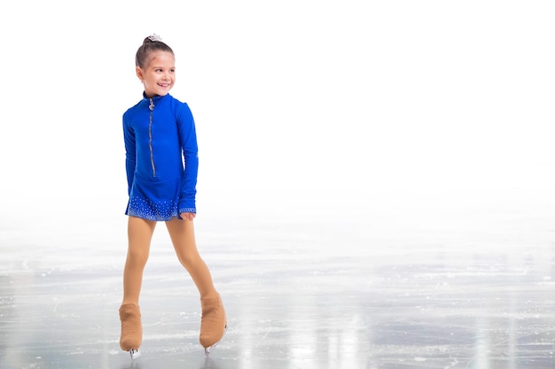 Un piccolo giovane pattinatore in posa in abito da allenamento blu su ghiaccio su sfondo bianco