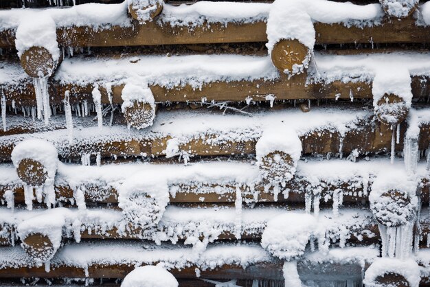 Un piccolo muro di piccoli tronchi sullo sfondo sotto la neve in inverno