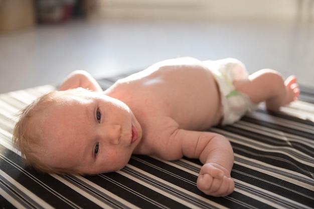 Un piccolo neonato con un pannolino bianco sdraiato sulla schiena