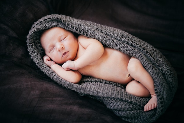 Un piccolo neonato giace su un plaid marrone