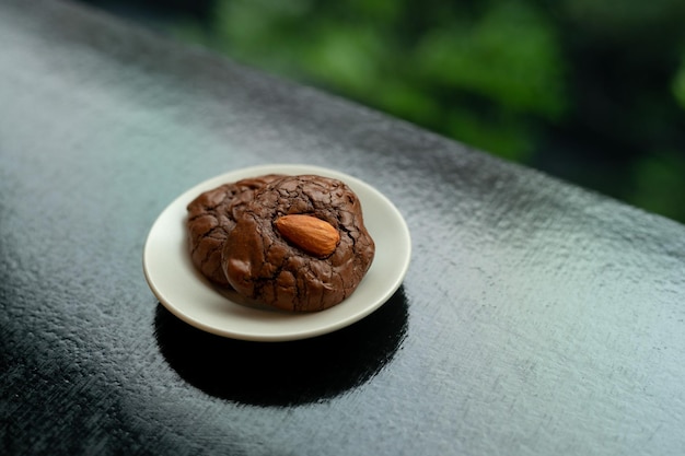 Un piccolo piatto di biscotti con gocce di cioccolato si trova su un bancone nero