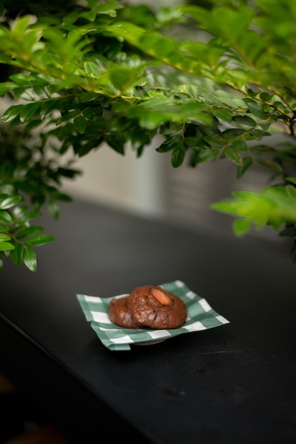 Un piccolo piatto di biscotti con gocce di cioccolato si trova su un bancone nero.