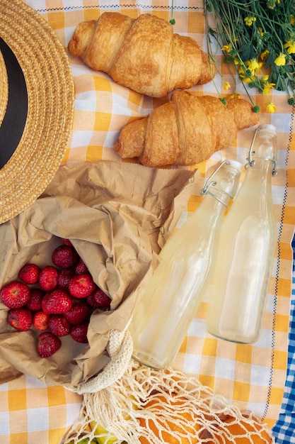 Un piccolo picnic con croissant fragole e limonata su una coperta a quadretti arancioni