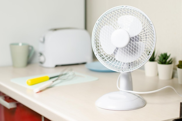 Un piccolo ventilatore sul tavolo della cucina Il concetto di raffreddamento e ventilazione della casa