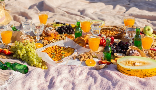 Un picnic nel parco con bellissimi bicchieri, frutta e pasticcini.