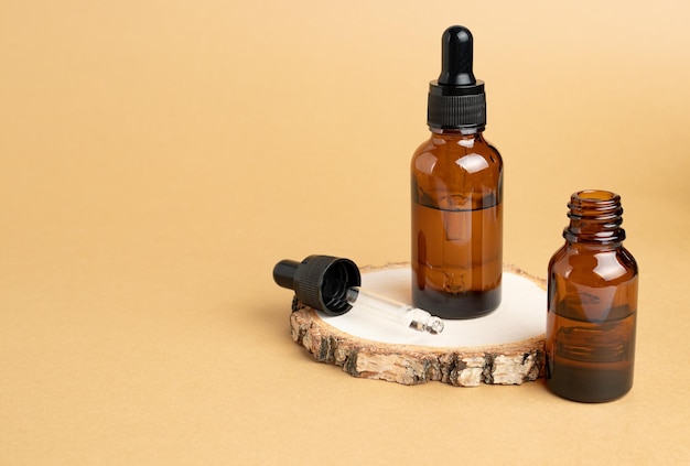 Un podio in legno e flaconi per pipette riempiti con olio o essenza Cosmetici naturali per la cura del corpo