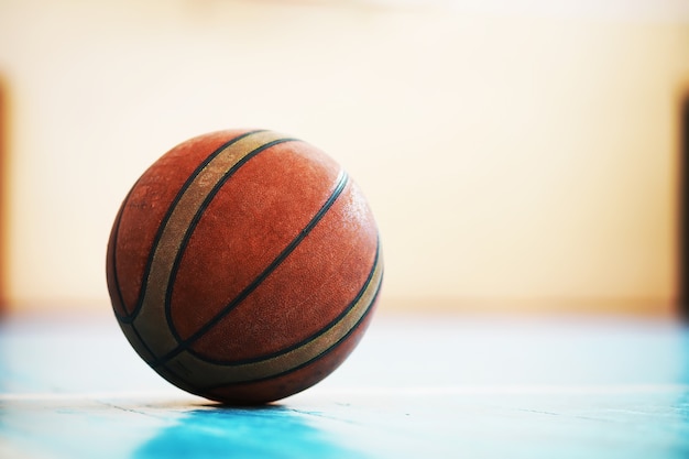 Un poggiapiedi umano sulla pallacanestro sul pavimento di cemento. Foto di una palla da basket e scarpe da ginnastica in un pavimento di legno.