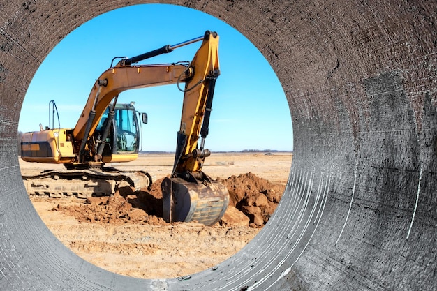 Un potente escavatore a cingoli scava il terreno contro il cielo blu Lavori di sterro con attrezzature pesanti in cantiere